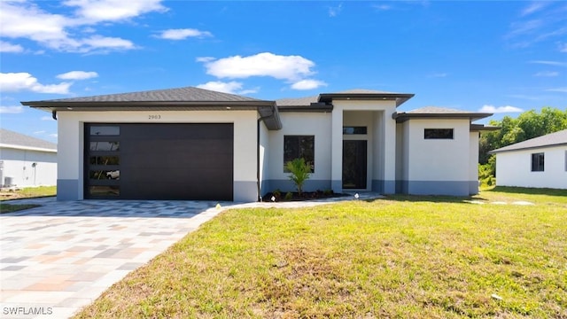 prairie-style home with a garage, a front lawn, decorative driveway, and stucco siding