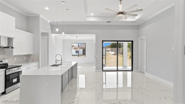 kitchen with wall chimney exhaust hood, open floor plan, modern cabinets, stainless steel range with electric stovetop, and baseboards