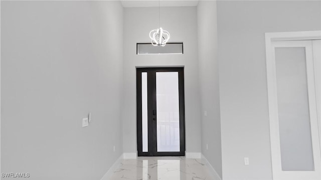 foyer with marble finish floor, baseboards, and an inviting chandelier