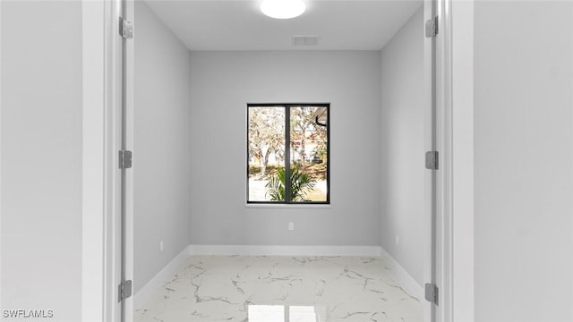 empty room with marble finish floor, baseboards, and visible vents