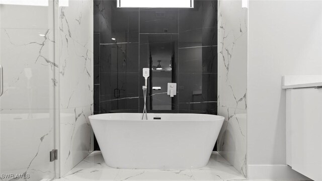 full bath featuring marble finish floor and a freestanding tub