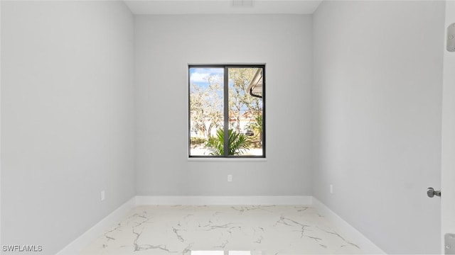 spare room featuring marble finish floor and baseboards