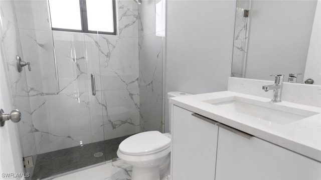 bathroom featuring toilet, marble finish floor, a marble finish shower, and vanity