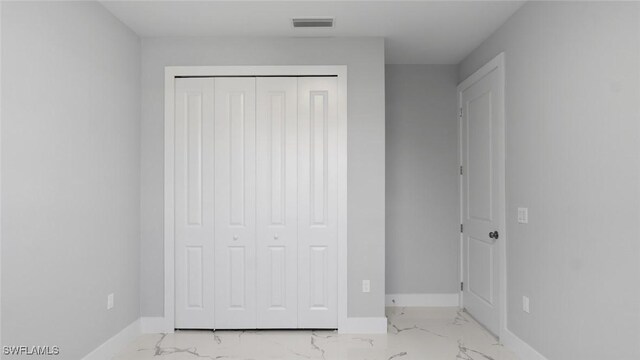 unfurnished bedroom featuring marble finish floor, baseboards, visible vents, and a closet