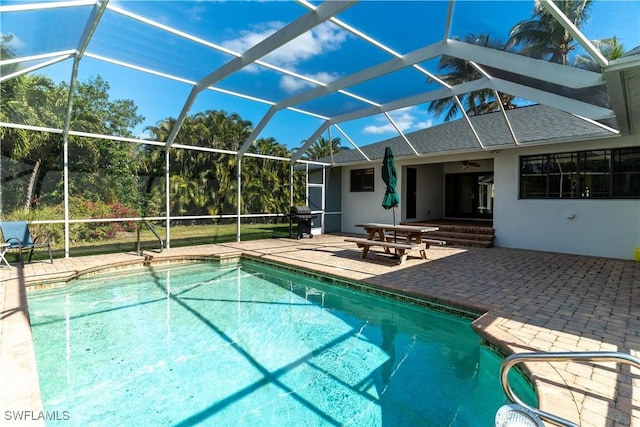 view of pool featuring grilling area, a patio, ceiling fan, and glass enclosure