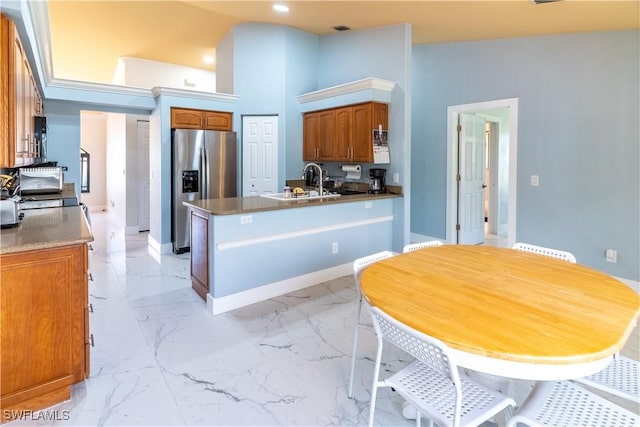 kitchen featuring a high ceiling, stainless steel refrigerator with ice dispenser, sink, and kitchen peninsula