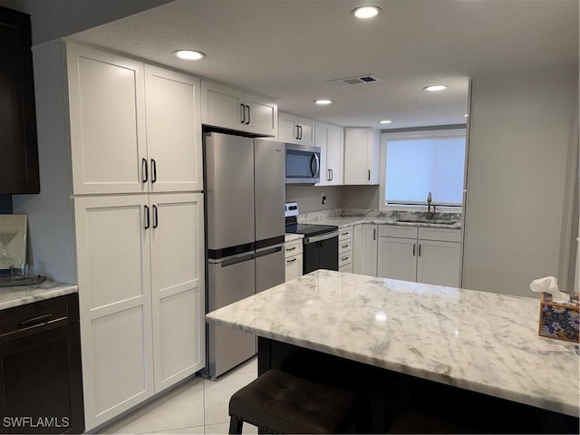 kitchen with white cabinetry, sink, stainless steel appliances, and light stone countertops