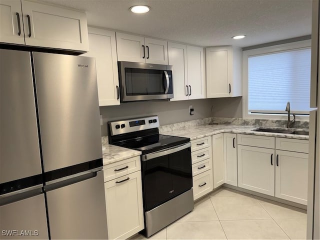 kitchen featuring white cabinetry, stainless steel appliances, sink, and light stone counters