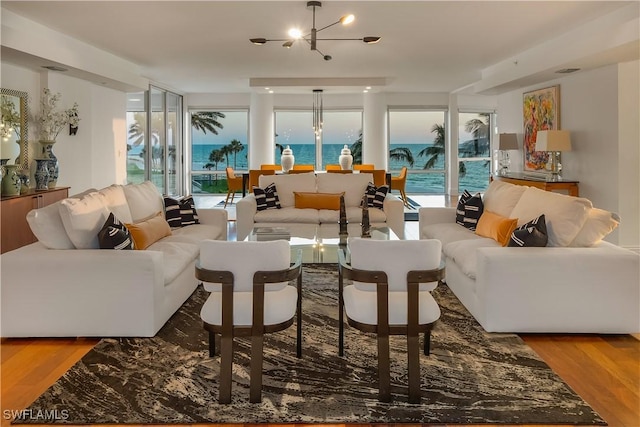 living room with a water view, wood-type flooring, and a chandelier