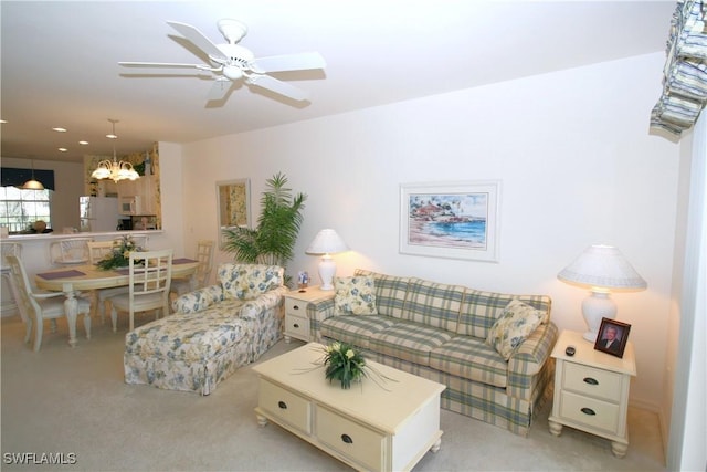 carpeted living room with ceiling fan with notable chandelier