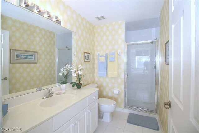 bathroom with tile patterned flooring, vanity, a shower with shower door, and toilet