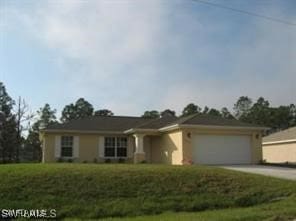 single story home featuring a garage and a front lawn