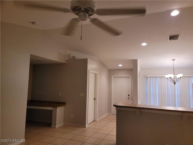 kitchen featuring pendant lighting, a kitchen bar, ceiling fan with notable chandelier, and light tile patterned floors