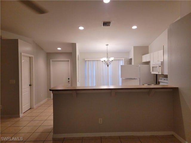 kitchen with white appliances, a breakfast bar area, white cabinetry, kitchen peninsula, and a chandelier