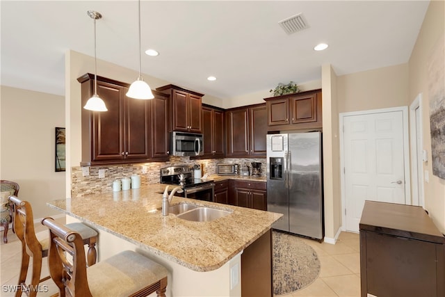 kitchen with tasteful backsplash, a breakfast bar area, hanging light fixtures, kitchen peninsula, and stainless steel appliances