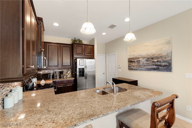 kitchen featuring appliances with stainless steel finishes, decorative light fixtures, light stone countertops, and sink