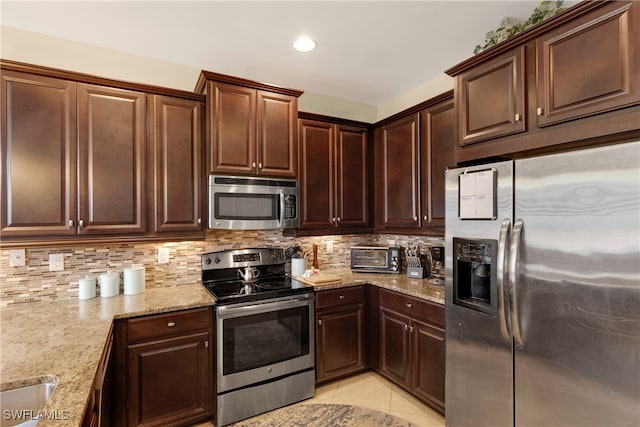 kitchen featuring light tile patterned floors, appliances with stainless steel finishes, backsplash, light stone counters, and dark brown cabinetry