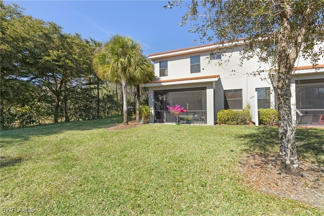 rear view of property with a sunroom and a lawn