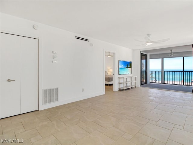 unfurnished living room with a water view and ceiling fan