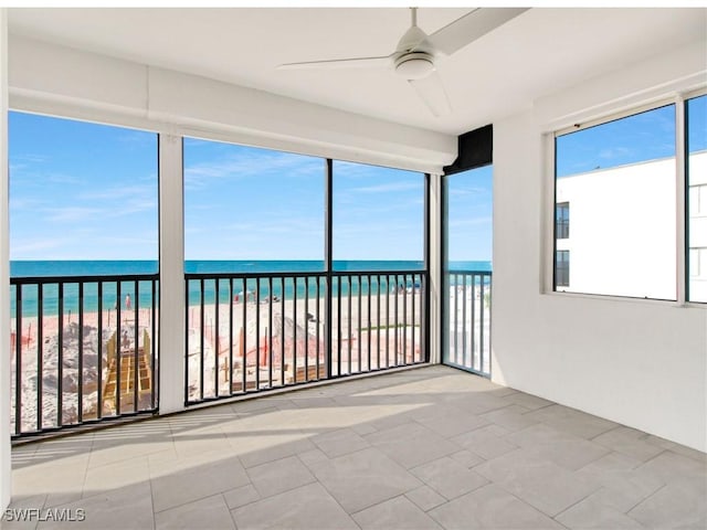 unfurnished sunroom featuring a view of the beach, a water view, and a healthy amount of sunlight