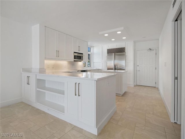 kitchen with stainless steel appliances, kitchen peninsula, and white cabinets