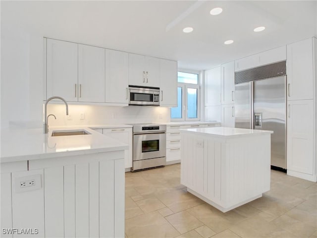 kitchen featuring appliances with stainless steel finishes, sink, a kitchen island, and white cabinets