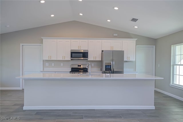 kitchen with a kitchen island with sink, sink, white cabinets, and appliances with stainless steel finishes