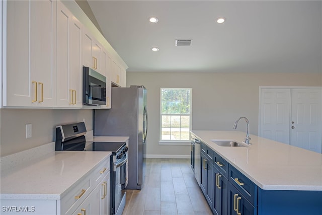 kitchen with blue cabinets, white cabinetry, appliances with stainless steel finishes, and sink