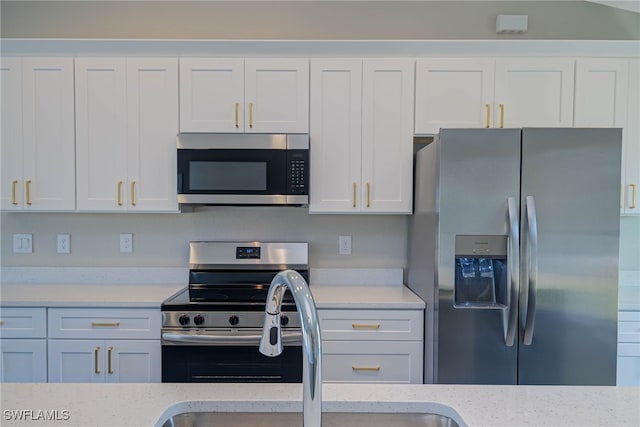 kitchen with light stone counters, stainless steel appliances, sink, and white cabinets