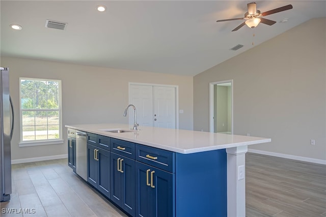 kitchen featuring lofted ceiling, sink, a kitchen island with sink, stainless steel appliances, and blue cabinetry