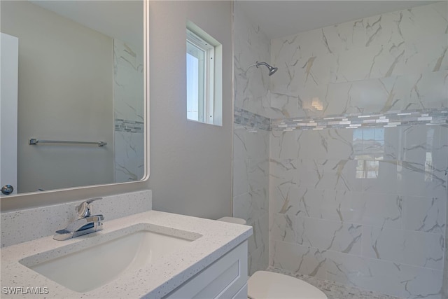 bathroom featuring vanity, toilet, and tiled shower