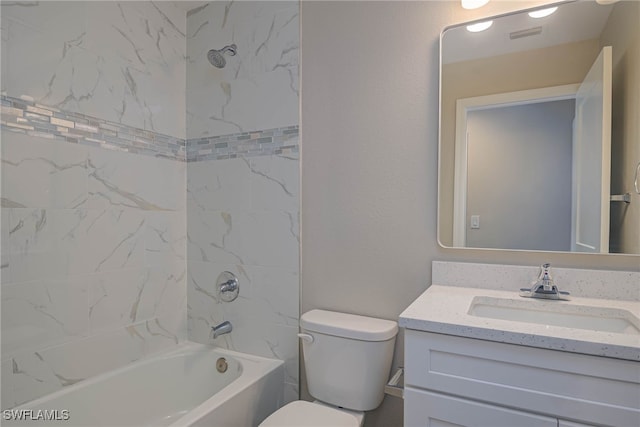 full bathroom featuring vanity, tiled shower / bath combo, and toilet