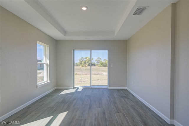 unfurnished room with a tray ceiling and dark hardwood / wood-style floors