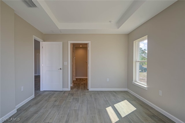 unfurnished bedroom featuring light hardwood / wood-style flooring and a raised ceiling