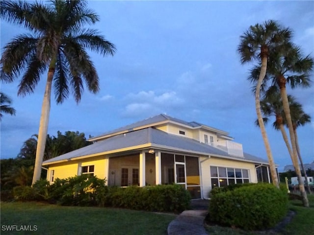 view of front facade with stucco siding, a front lawn, and a balcony