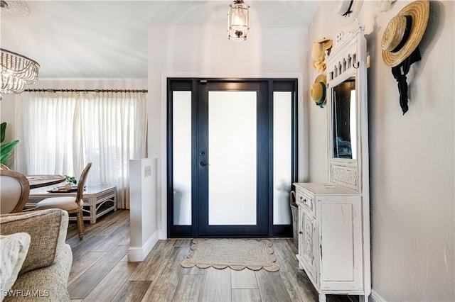 foyer entrance with hardwood / wood-style flooring and a chandelier