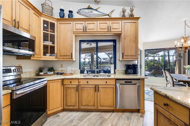 kitchen featuring sink, hanging light fixtures, a notable chandelier, stainless steel appliances, and light stone countertops