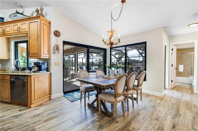 dining space featuring lofted ceiling, sink, light hardwood / wood-style flooring, and a chandelier