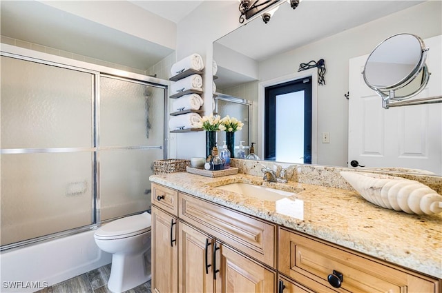 full bathroom featuring vanity, hardwood / wood-style flooring, bath / shower combo with glass door, and toilet