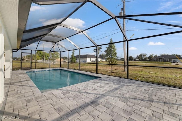 view of swimming pool featuring a yard, glass enclosure, and a patio area