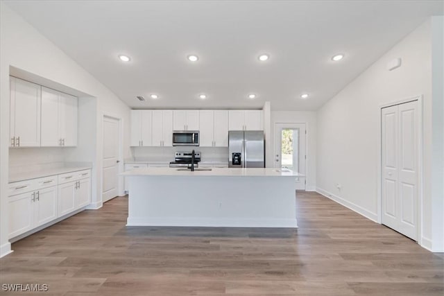 kitchen featuring an island with sink, appliances with stainless steel finishes, sink, and white cabinets