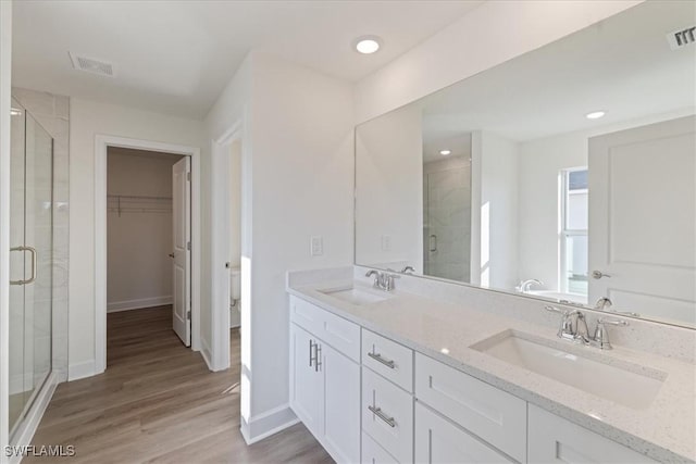 bathroom with walk in shower, vanity, and wood-type flooring