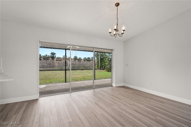 unfurnished room featuring an inviting chandelier and wood-type flooring