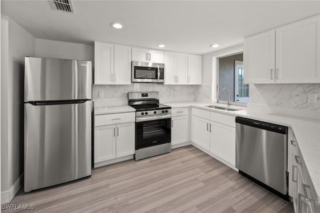 kitchen with white cabinetry, appliances with stainless steel finishes, light hardwood / wood-style floors, and sink