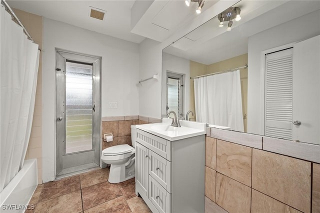 full bathroom featuring shower / bath combo with shower curtain, vanity, toilet, and tile walls