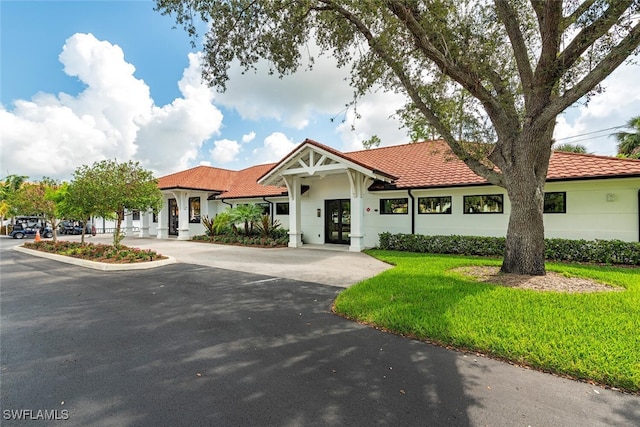 view of front of home with driveway, a tiled roof, and a front lawn