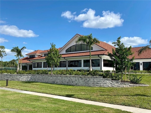 view of front facade with a tile roof and a lawn