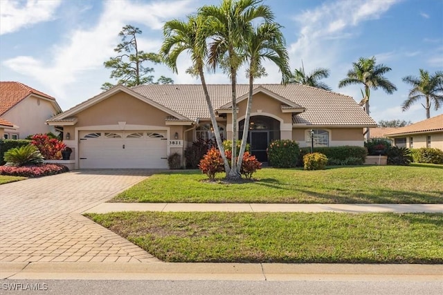 single story home with a garage, decorative driveway, a front yard, and stucco siding