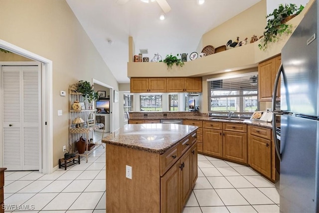 kitchen with light tile patterned flooring, appliances with stainless steel finishes, brown cabinets, and a center island