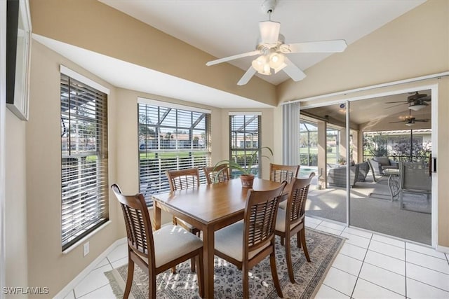 dining area featuring lofted ceiling, a sunroom, light tile patterned flooring, ceiling fan, and baseboards